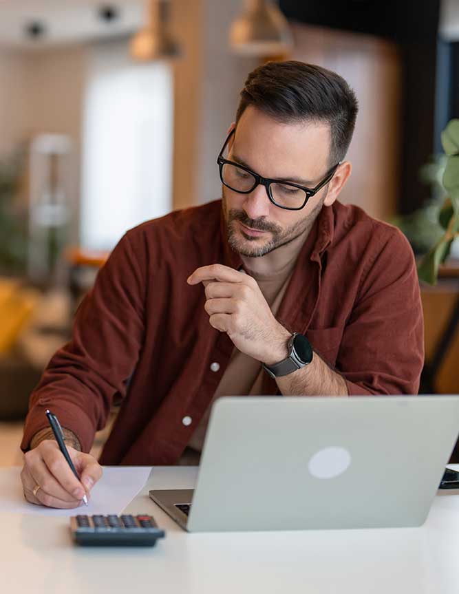 business-owner-computer-calculator-financial-planning Business owner using calculator and computer to help with financial planning
